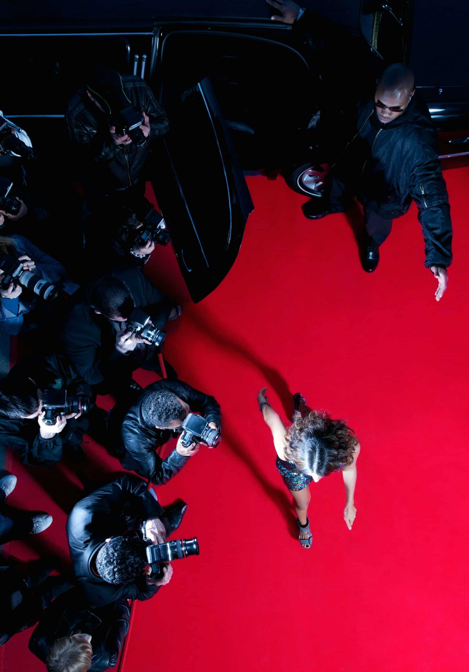 Stressed celebrity covering face during media backlash.