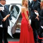Celebrity walking red carpet in red dress while paparazzi and reporters surround h