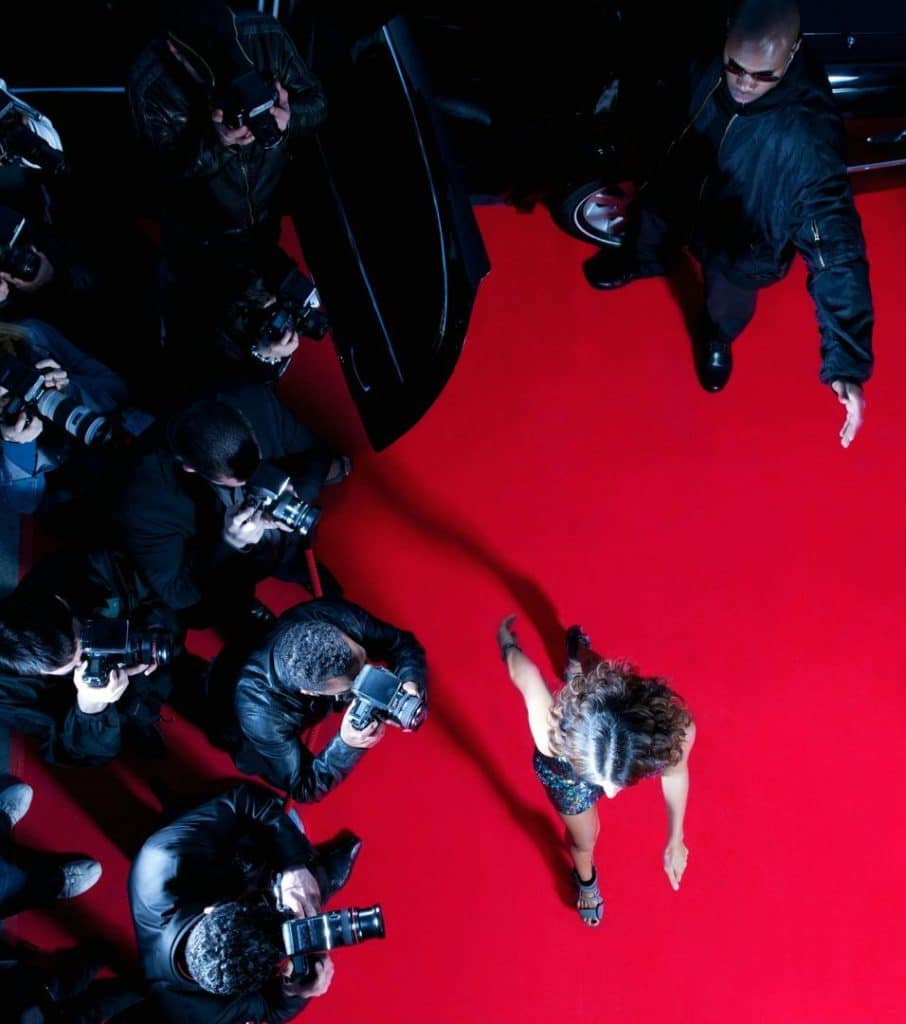 Stressed celebrity covering face during media backlash.
