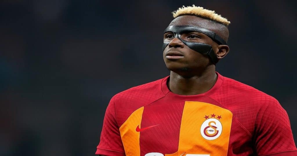 Professional footballer in a red and yellow Galatasaray jersey wearing a black face mask during a match